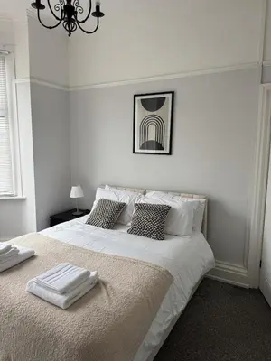 a white bedroom with a large bed with two towels on it at Month Stays Central 3 bed Three Bedroom House by Brookland Stays Serviced Accommodation & Short Lets in Preston with Free WiFi in Farington
