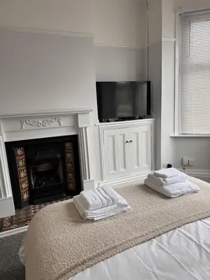 a bedroom with two towels on a bed with a fireplace at Month Stays Central 3 bed Three Bedroom House by Brookland Stays Serviced Accommodation & Short Lets in Preston with Free WiFi in Farington
