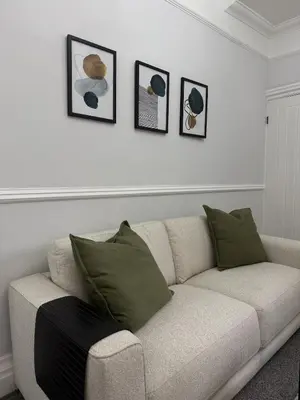 a white couch in a living room with four pictures on the wall at Month Stays Central 3 bed Three Bedroom House by Brookland Stays Serviced Accommodation & Short Lets in Preston with Free WiFi in Farington