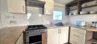 a kitchen with white cabinets and a stove top oven at BILOT Caravan in Heysham
