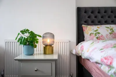 a bed with a table with a lamp and a plant at Modern & Stylish Stay in the Heart of St Hubert in Great Harwood