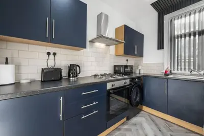 a kitchen with blue cabinets and a stove top oven at Modern & Stylish Stay in the Heart of St Hubert in Great Harwood