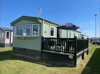 a green tiny house with an umbrella on the deck at Seaside Arizona in Morecambe