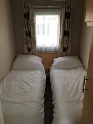 two beds in a small room with a window at Seaside Arizona in Morecambe