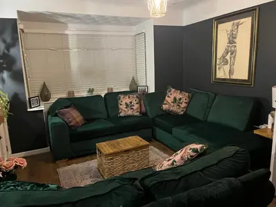 a living room with a green couch and a table at Our Happy Place West Derby in Deysbrook