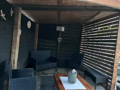 a patio with chairs and a table and a clock at Our Happy Place West Derby in Deysbrook