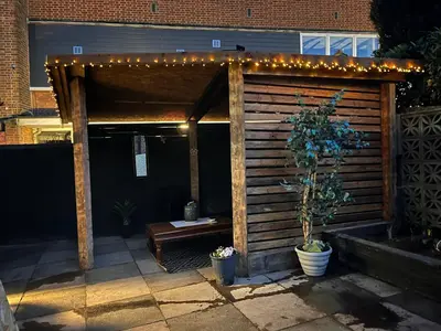 a pergola with lights and a bench on a patio at Our Happy Place West Derby in Deysbrook