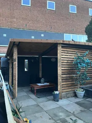 a wooden pavilion with a wooden table in front of a building at Our Happy Place West Derby in Deysbrook