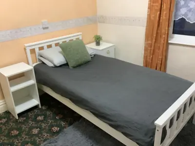 a bedroom with a white bed with a green pillow at King Edward Guesthouse in Blackpool