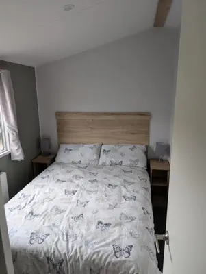 a bedroom with a large bed with a wooden headboard at T&K's Caravan in Morecambe