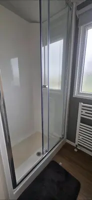 a glass shower in a room with a window at T&K's Caravan in Morecambe