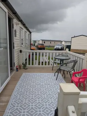 a patio with a table and chairs on a deck at T&K's Caravan in Morecambe
