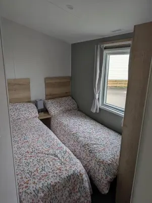 two beds in a small room with a window at T&K's Caravan in Morecambe