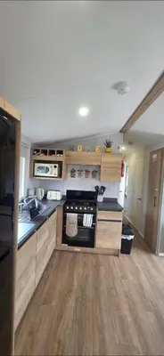 a kitchen with wooden cabinets and a stove top oven at T&K's Caravan in Morecambe
