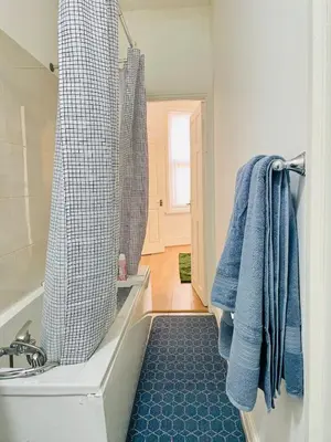 a bathroom with a tub and a shower with blue towels at Cozy Cottage in Liverpool