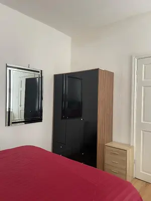 a bedroom with a bed and a dresser and a mirror at Cozy Cottage in Liverpool