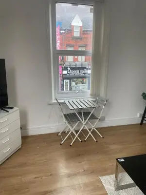 a room with a chair in front of a window at Cozy Cottage in Liverpool