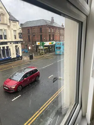 a red car parked on a city street from a window at Cozy Cottage in Liverpool