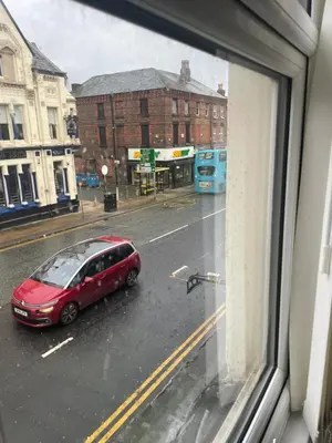 a red car parked on a city street from a window at Cozy Cottage in Liverpool