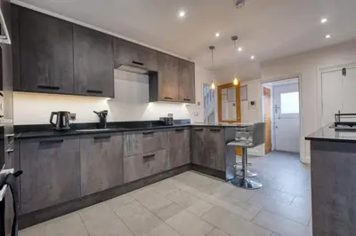 a kitchen with wooden cabinets and a counter top at Westhoughton 3 Bedroom House - Free Parking in Westhoughton