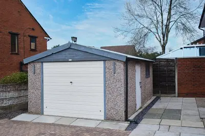 a white garage door on a brick building at Westhoughton 3 Bedroom House - Free Parking in Westhoughton