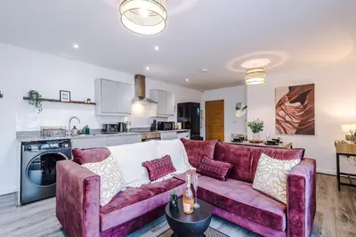 a living room with a purple couch and a kitchen at Centrally Located Formby Flat by 53 Degrees Property, Perfect for Work & Leisure in Formby