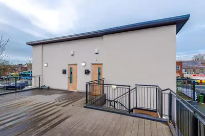 a large white building with a wooden deck at Centrally Located Formby Flat by 53 Degrees Property, Perfect for Work & Leisure in Formby