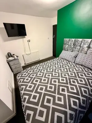 a bedroom with a bed and a green wall at The Coningsby Staycation in Liverpool