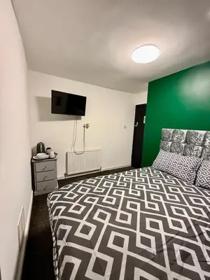 a bedroom with a bed and a green wall at The Coningsby Staycation in Liverpool