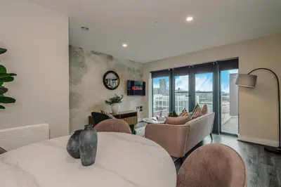 a bedroom with a bed and chairs and a living room at Luxury 2-Bed Apt by Royal Albert Dock & M&S Arena in Liverpool