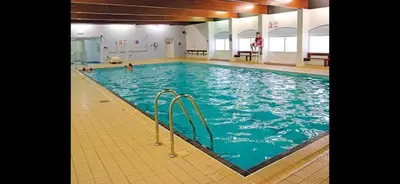 a large swimming pool with blue water in a building at Shellie's Summer Breeze Retreat in Heysham