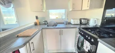 a kitchen with white cabinets and a stove top oven at Shellie's Summer Breeze Retreat in Heysham