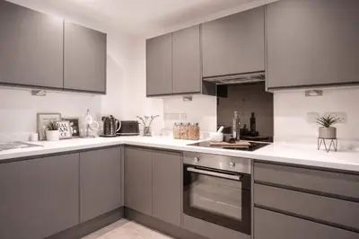 a kitchen with gray cabinets and white counter tops at Poets Place Penthouse in Liverpool