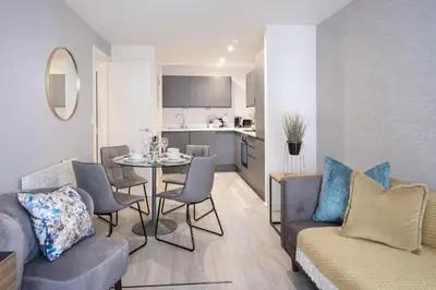 a living room with a table and chairs and a kitchen at Poets Place Penthouse in Liverpool