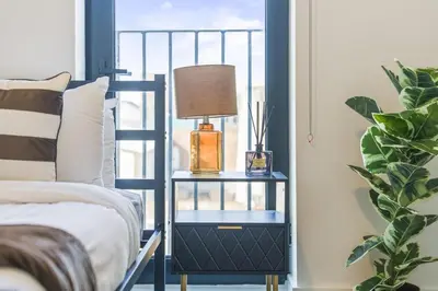 a nightstand with a lamp on it next to a bed at Oriel Residence - 2BR - 4 Beds - Sleeps 5 in Liverpool