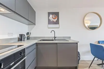 a white kitchen with a sink and a mirror at Oriel Residence - 2BR - 4 Beds - Sleeps 5 in Liverpool