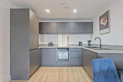 a kitchen with gray cabinets and a blue chair at Oriel Residence - 2BR - 4 Beds - Sleeps 5 in Liverpool