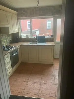 a kitchen with white cabinets and a sink and a window at 2 bedroom house in Horwich