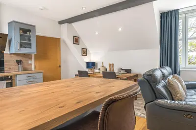 a kitchen and dining room with a wooden table and chairs at Abbey Apartments - Modern Serviced Apartments - Tourists & Professionals in Barrow in Furness