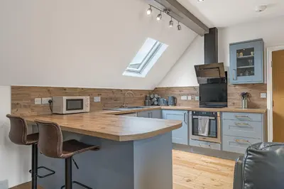 a kitchen with blue cabinets and a counter with a microwave at Abbey Apartments - Modern Serviced Apartments - Tourists & Professionals in Barrow in Furness