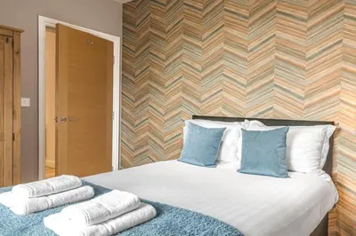 a bedroom with a bed with towels on it at Abbey Apartments - Modern Serviced Apartments - Tourists & Professionals in Barrow in Furness