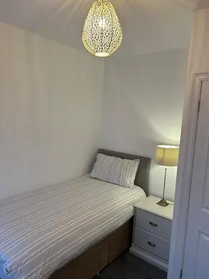 a small bedroom with a bed and a chandelier at Beautiful 3 bedroom home, Dorrington Terrace in Lancaster