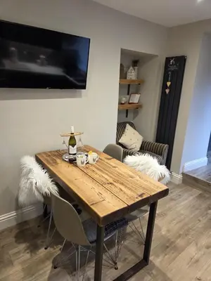 a dining room table with chairs and a tv at May Cottage, Ulverston in Greenodd