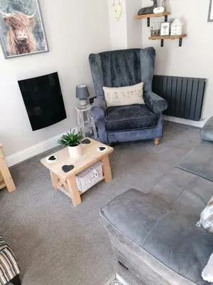 a living room with a couch and a chair and a tv at May Cottage, Ulverston in Greenodd