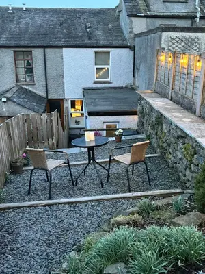 a patio with two chairs and a table in front of a building at May Cottage, Ulverston in Greenodd