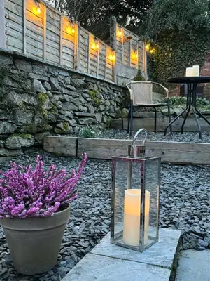 a candle in a glass box next to a pot of flowers at May Cottage, Ulverston in Greenodd