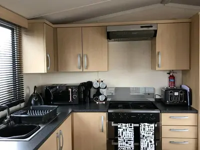 a kitchen with wooden cabinets and a stove top oven at Charming Holiday Park Retreat in Morecambe - Family-Friendly Escape in Morecambe