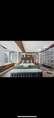 a bedroom with a large bed with a green blanket at Stylish Studio Apartment in Liverpool