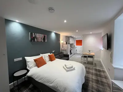 a bedroom with a large bed and a living room at Avenham Apartments in Preston