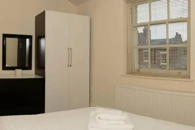 a white bedroom with a bed and a window at Avenham Apartments in Preston
